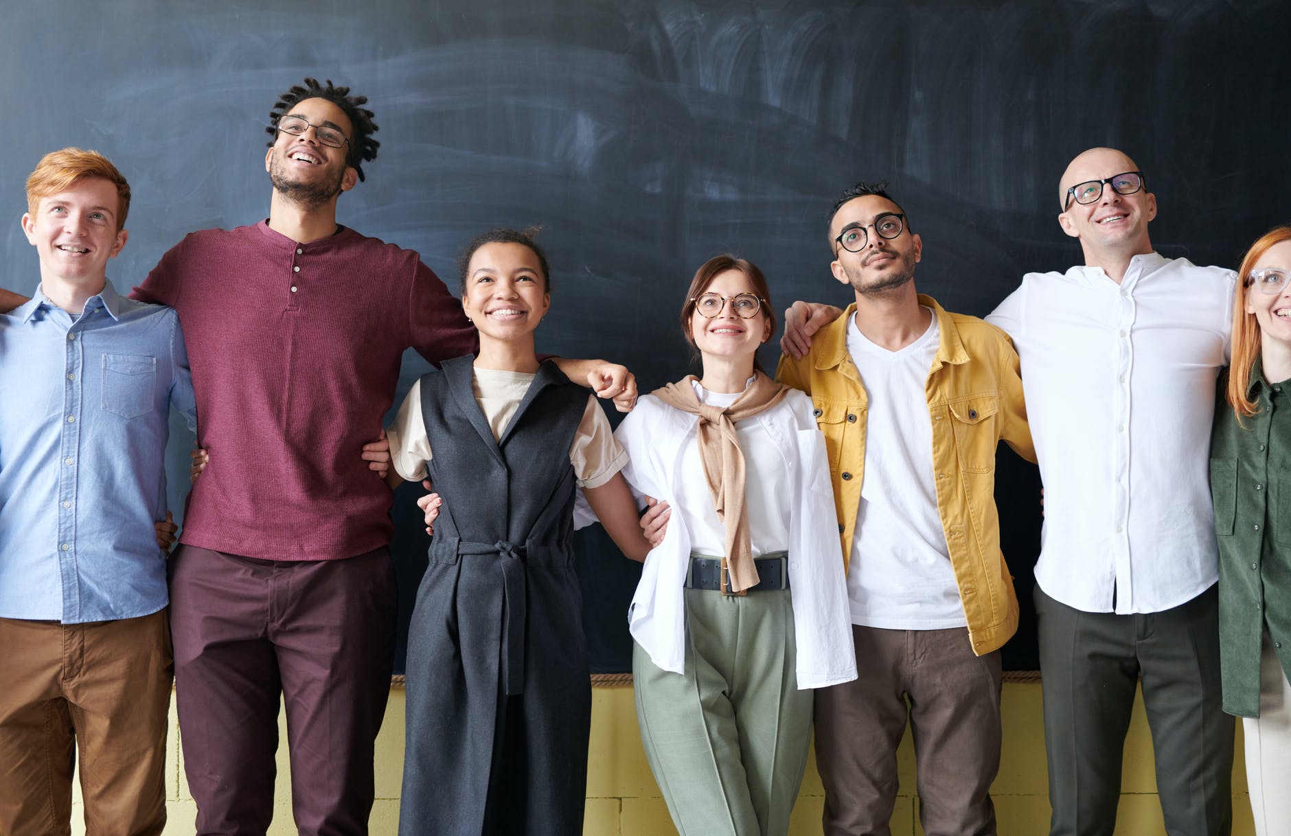 A group of diverse people standing side by side with smiles on their faces